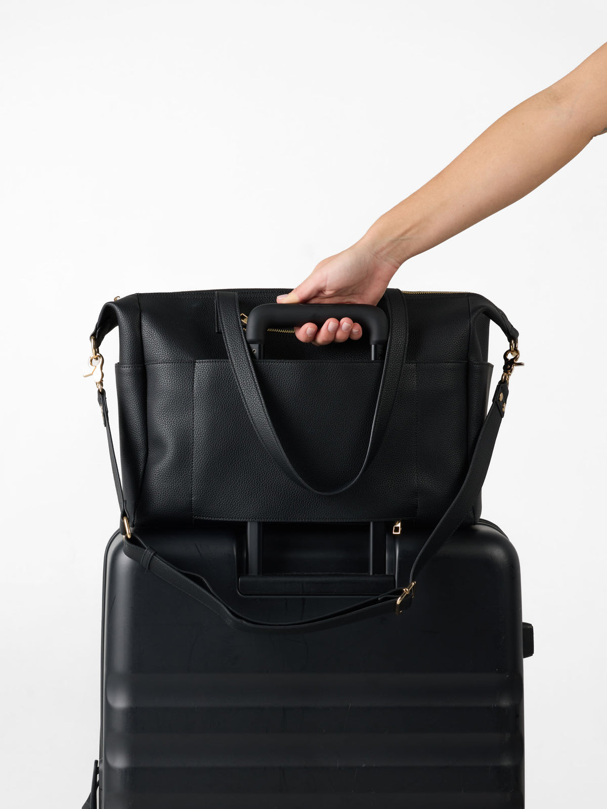 Black vegan leather nappy bag sitting on top of a suitcase using it's luggage