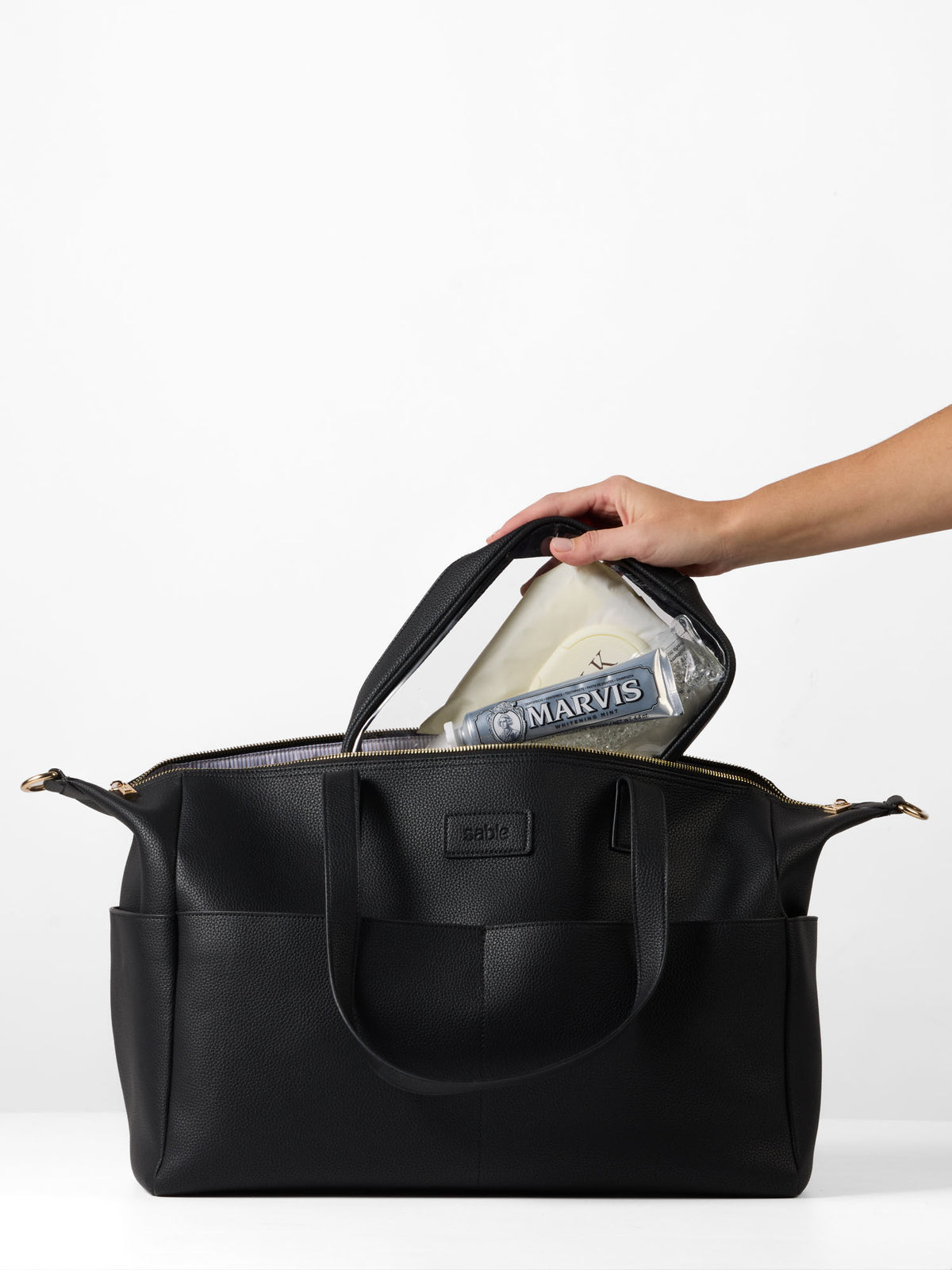 Clear organiser case being packed into the black vegan leather Carryall Bag