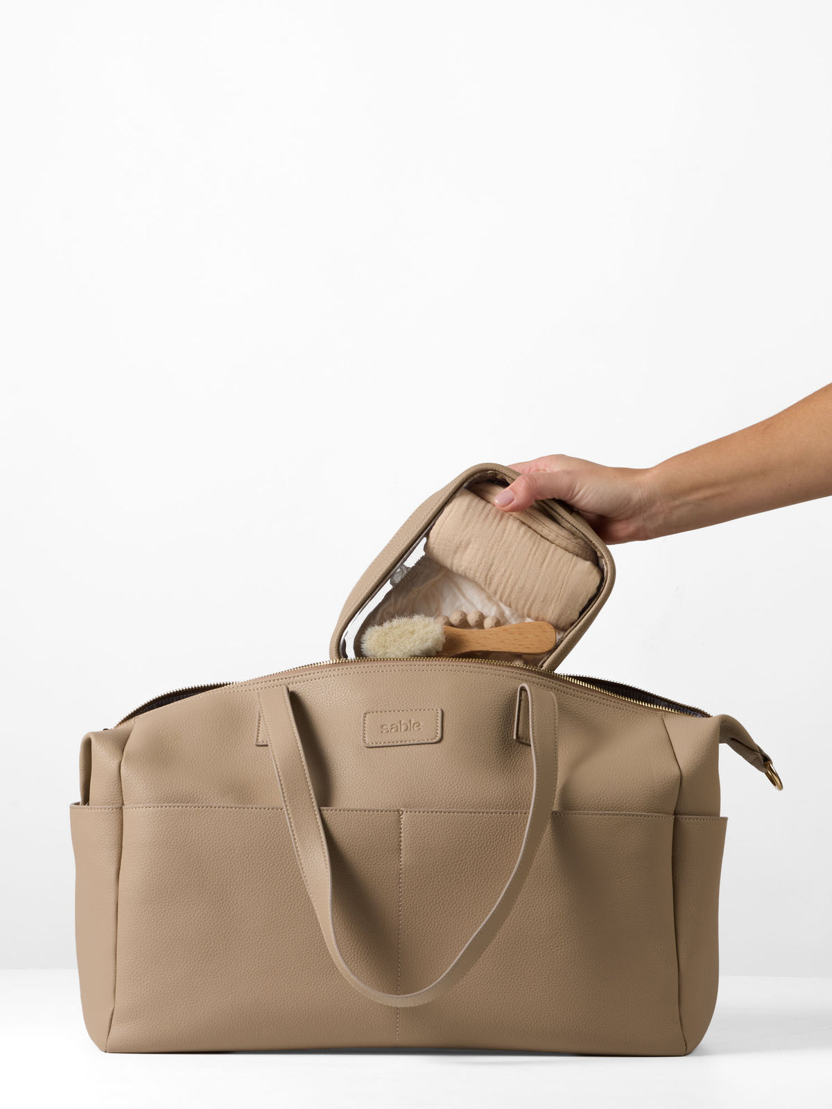 Clear organiser case being packed into the taupe vegan leather Carryall Bag