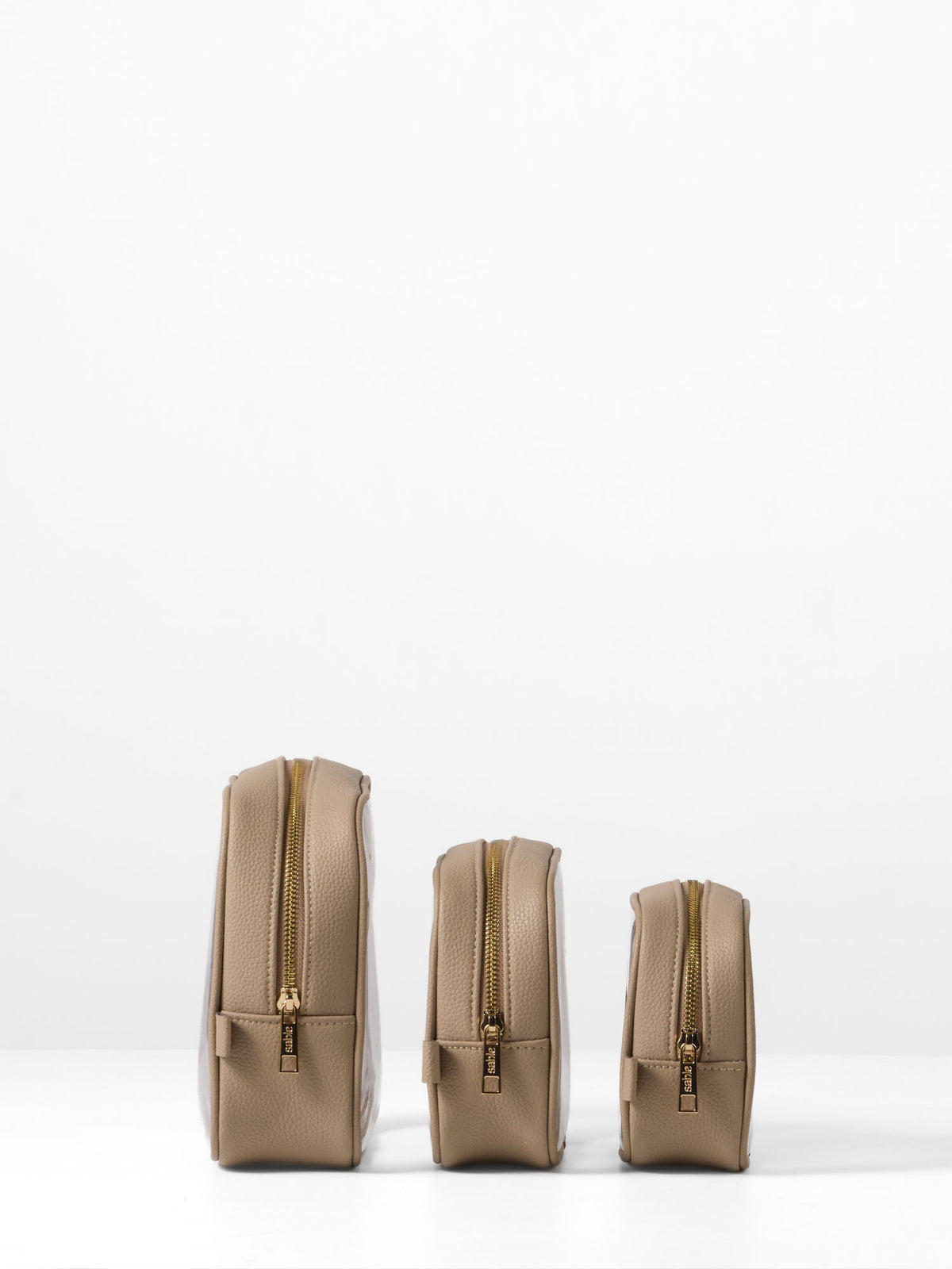 Side view of the three taupe-trim organiser cases showing their gold zips