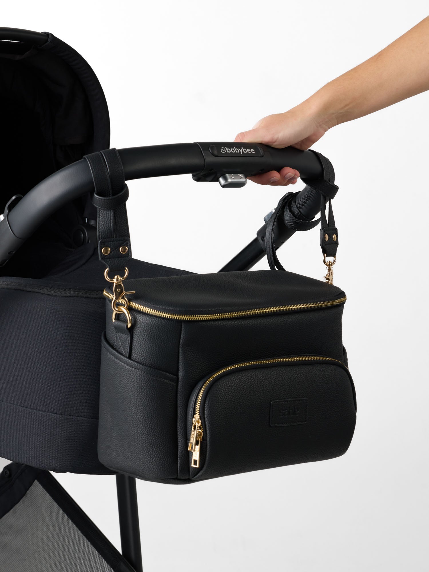 Black Vegan leather pram caddy attached to stroller storing nappies, wipes, bottles and baby essentials