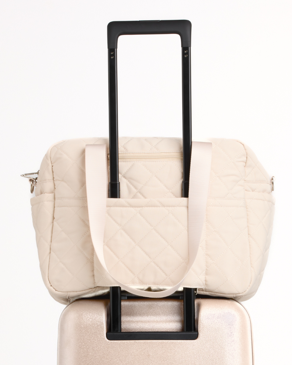 Back of the sand quilted nappy bag on a suitcase handle