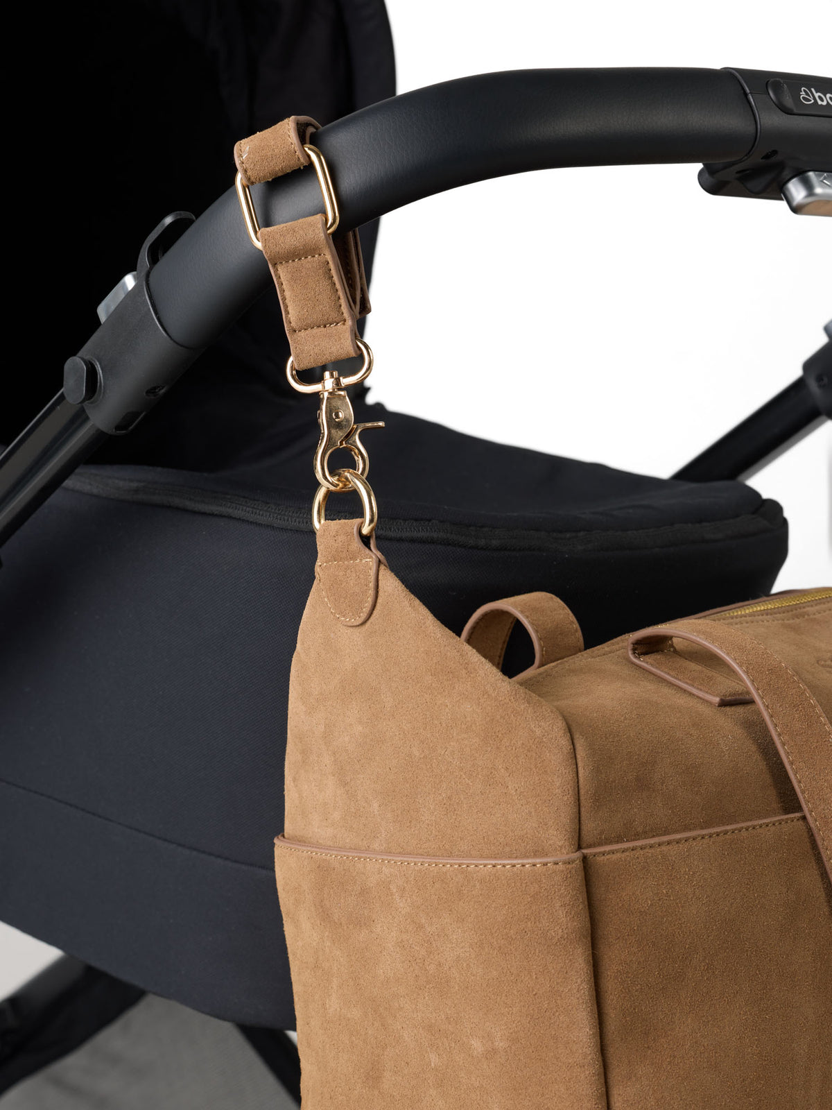 Close up image of a suede nappy bag with suede pram straps attached top a black baby bee stroller handle - Sable Bebe