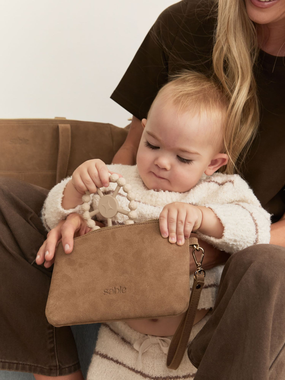 Mother and Baby holding a Suede zipped pouch that matches a suede nappy Bag - Sable Bebe