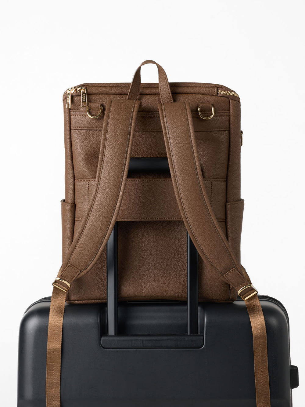 Chocolate nappy backpack on a suitcase handle via its luggage sleeve