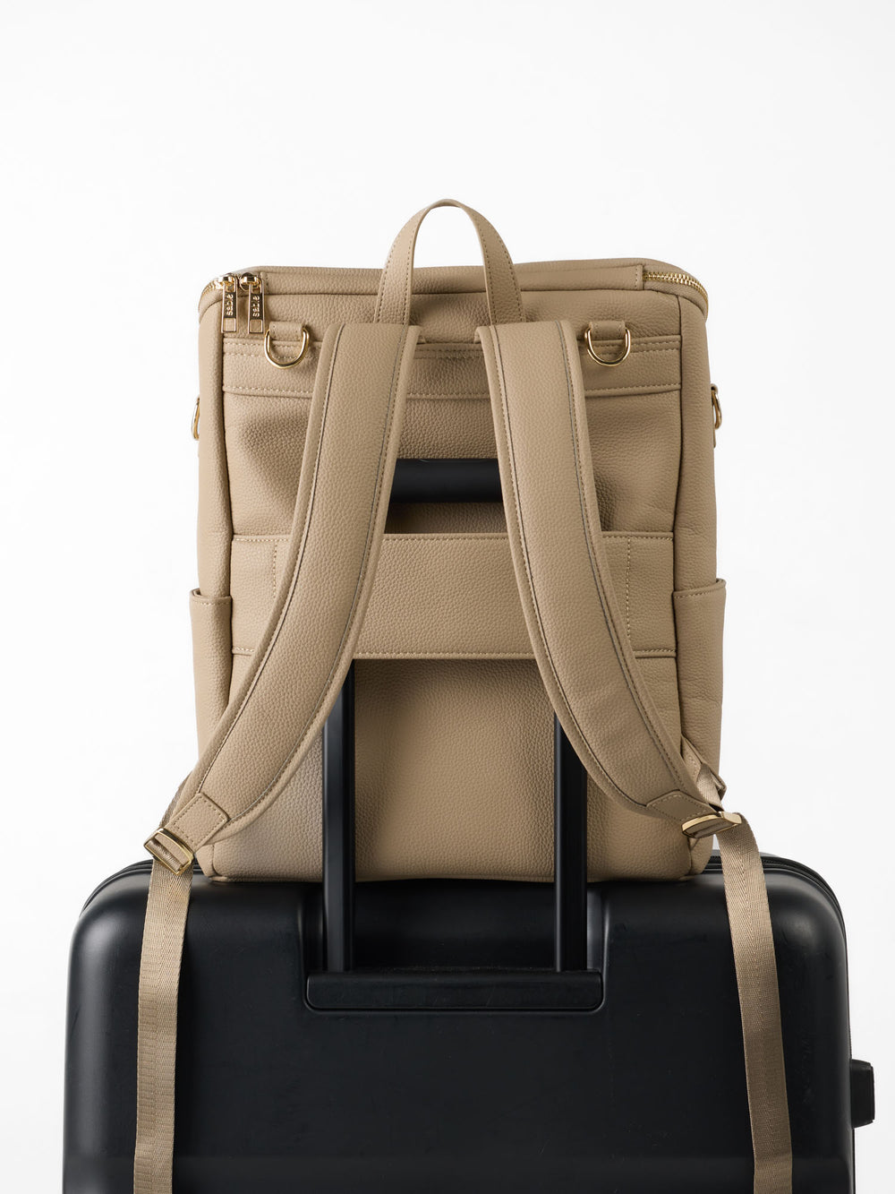 Taupe nappy backpack on a suitcase handle via its luggage sleeve