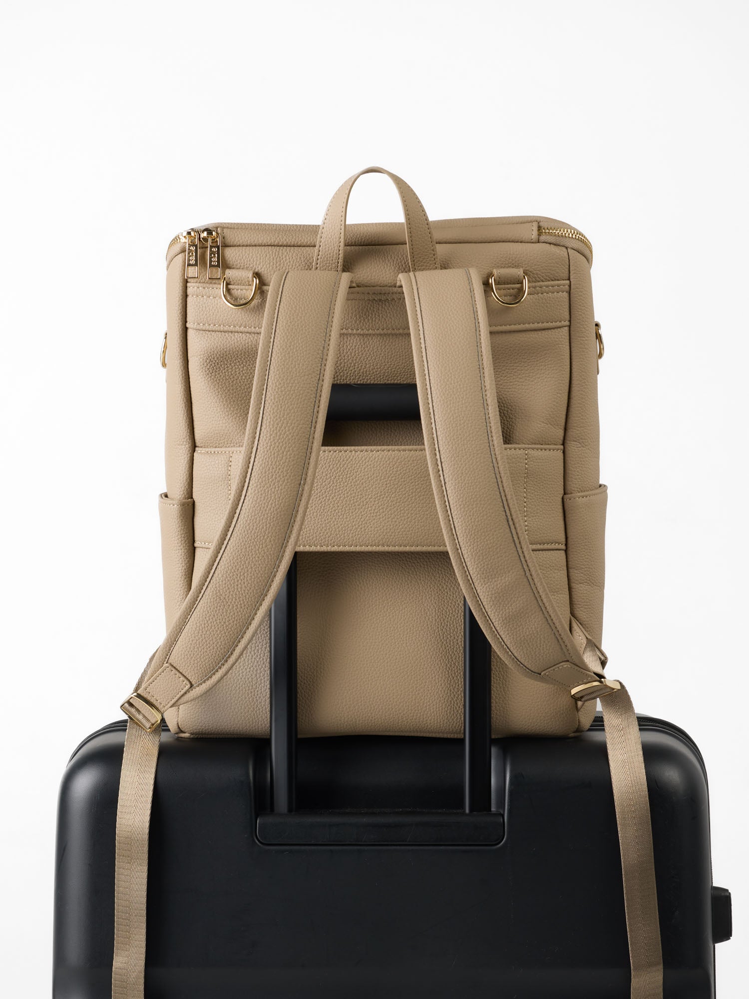 Vegan leather nappy backpack attached to a suitcase using the rear luggage sleeve for travel