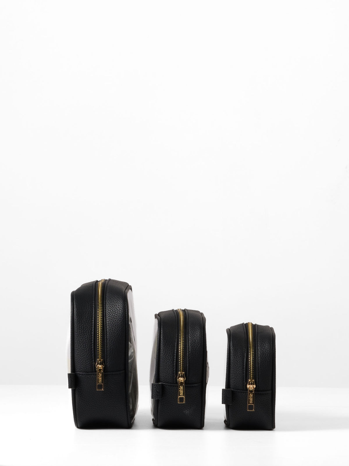 Side view of the three black-trim organiser cases showing their gold zips