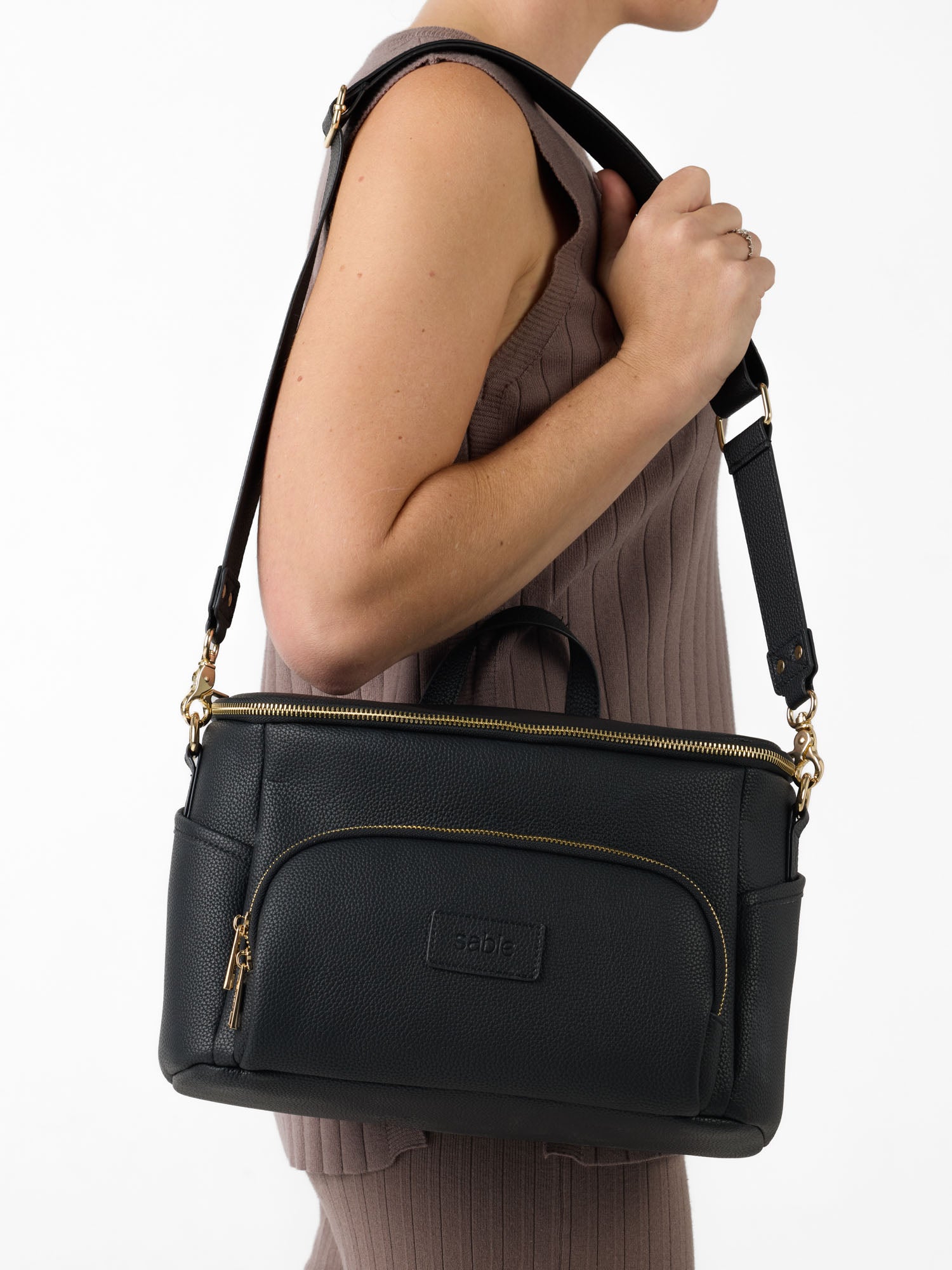 Black vegan leather pram caddy worn as a crossbody baby bag with adjustable shoulder strap