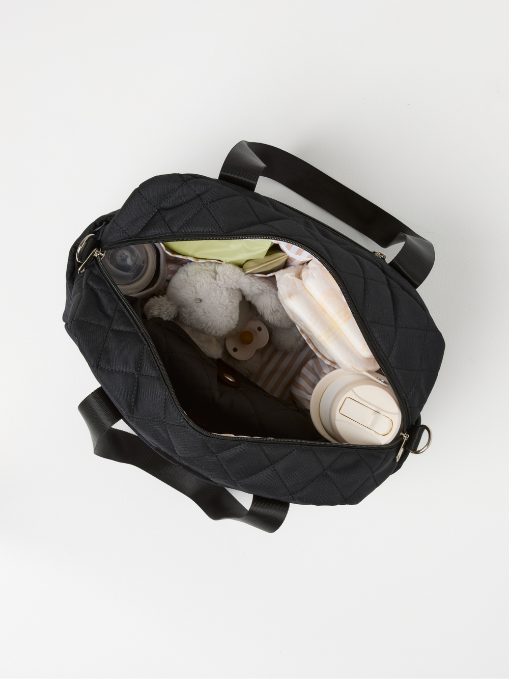 Top view of the open black quilted nappy bag packed with baby essentials