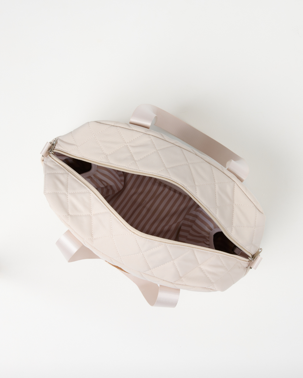 Top view of the open sand quilted nappy bag showing its striped lining