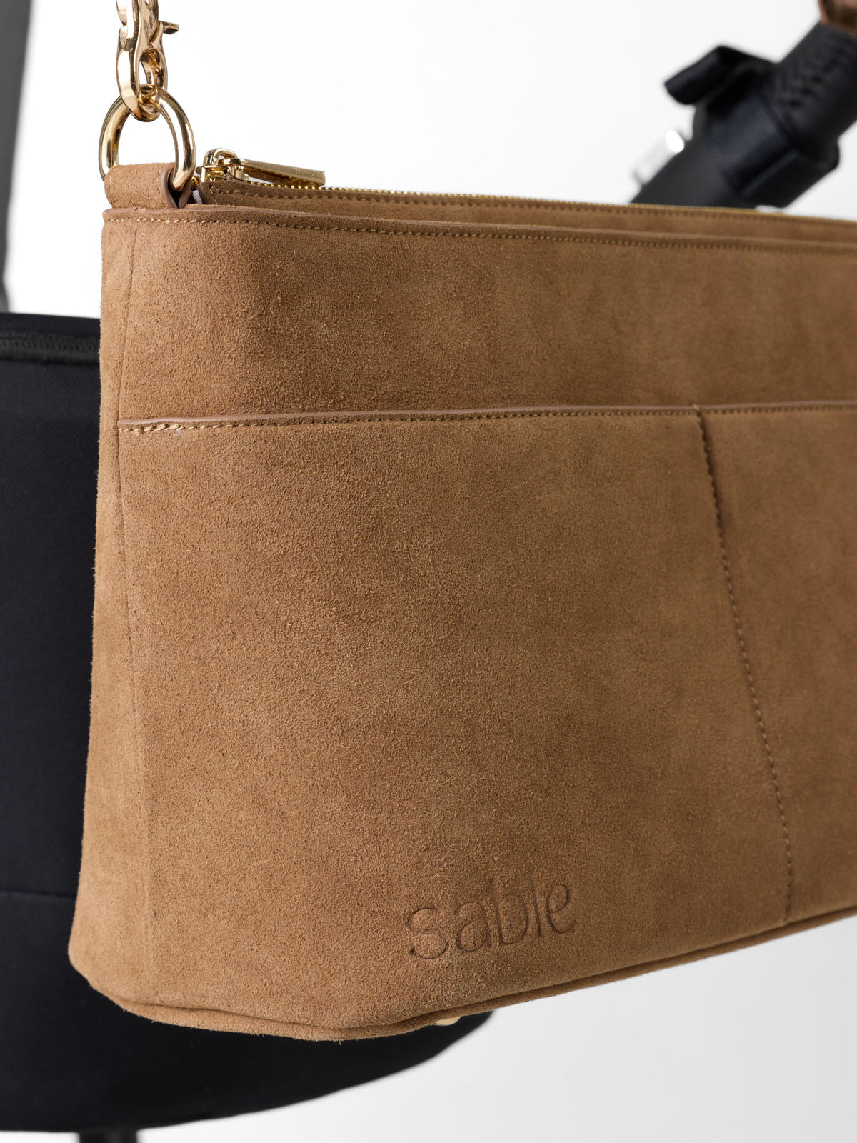 A close-up of a tan suede pram caddy bag with a front pocket and the brand name 'sable' embossed on the bottom right, shown against a white background with the baby bee stroller - Sable Bebe