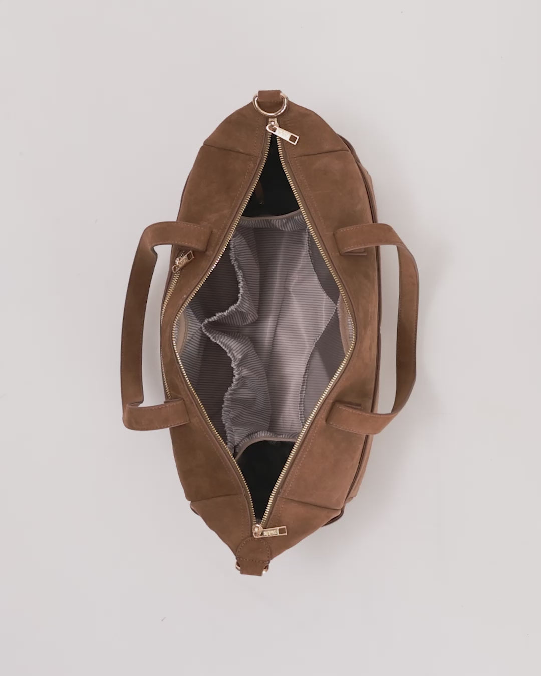 aerial view of a brown suede nappy tote bag being packed with all nappy bag essential items for the day - sable bebe