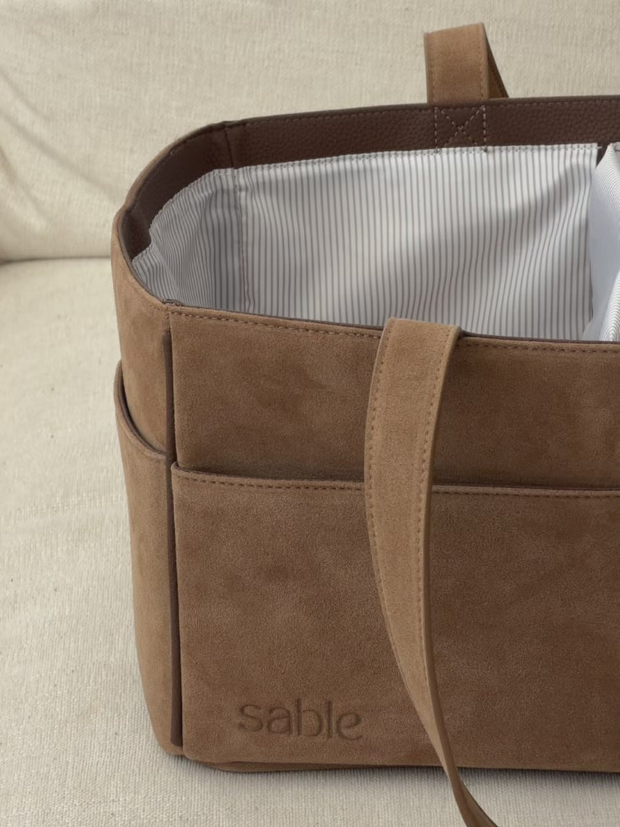 Video of the Sable Bebe Brown Suede Nappy Caddy being stocked full of baby essentials such as nappies, wipes, toys and creams that will be used at change time