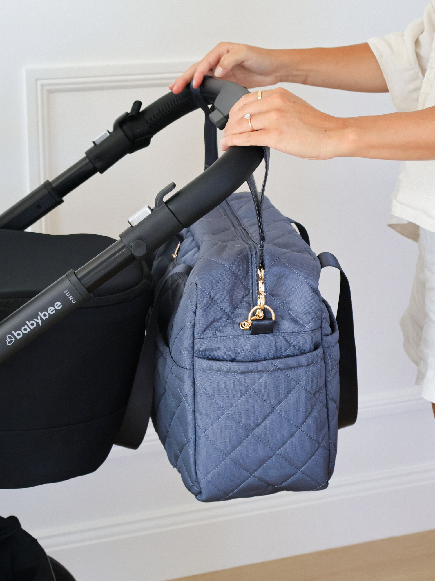 Blue quilted diaper bag attached to a black stroller